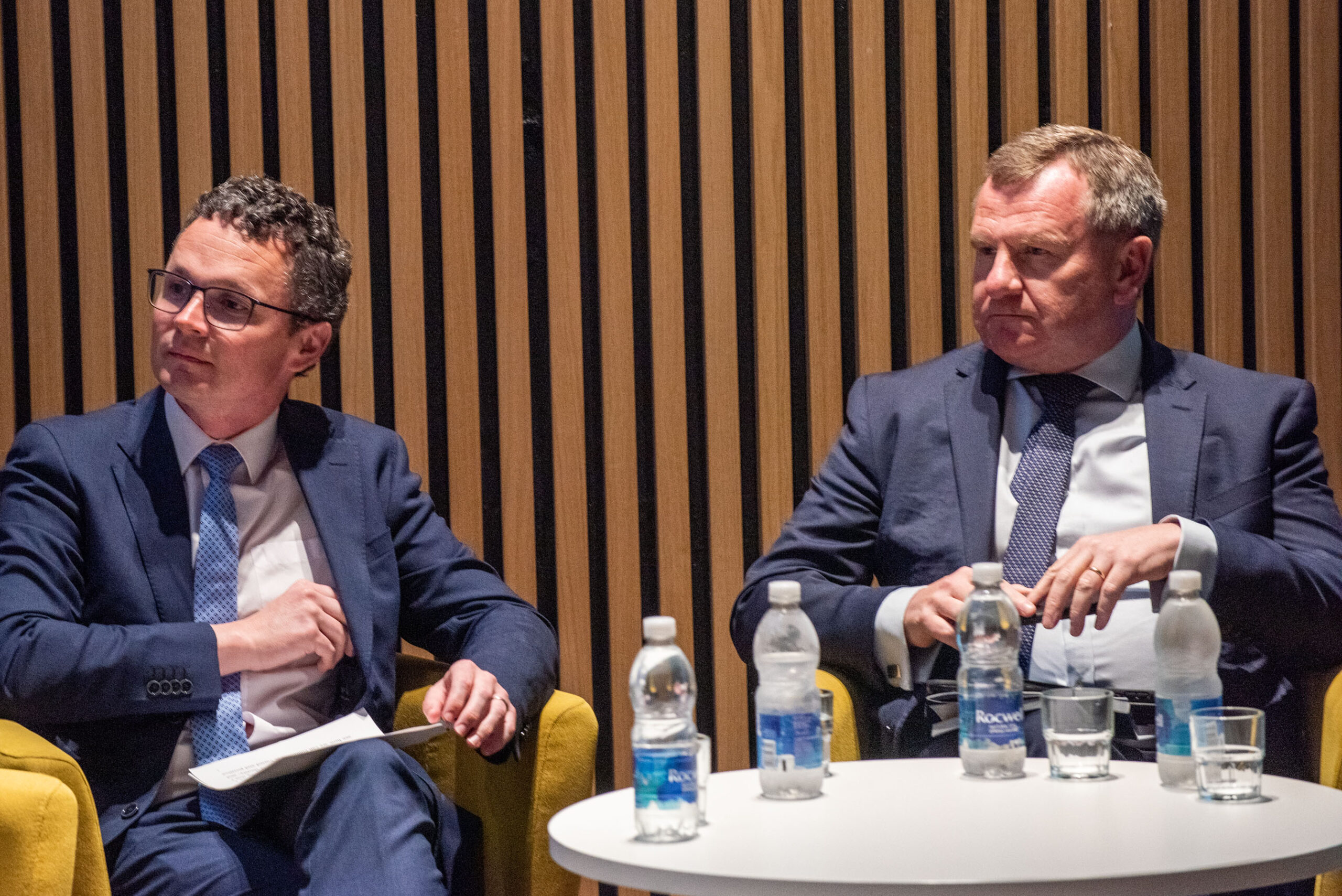 Two gentlemen sitting on stage engaged in a panel discussion